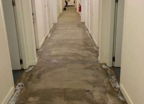 A hallway with concrete floors and white walls.