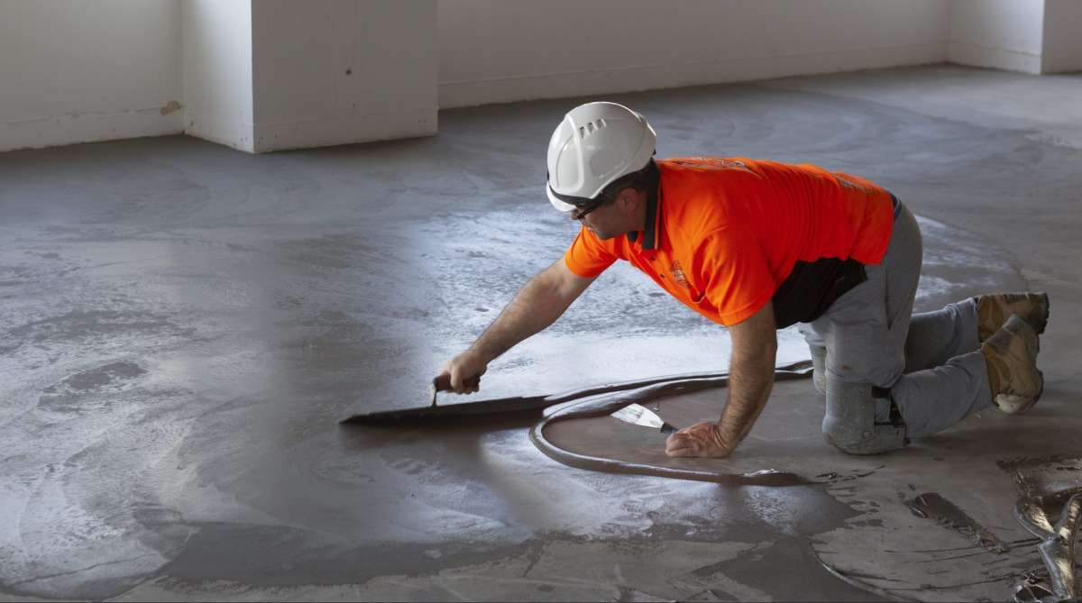 A man in an orange shirt is using a sanding disc