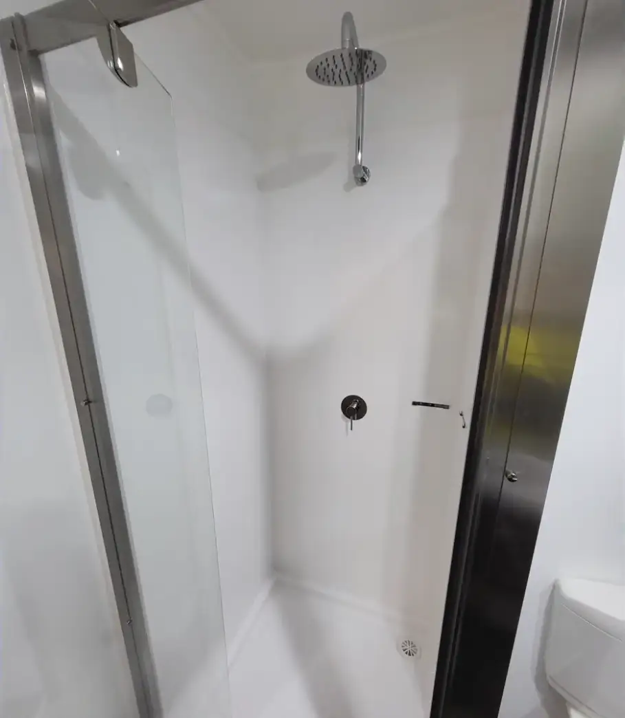 A shower with a door open and a mirror.