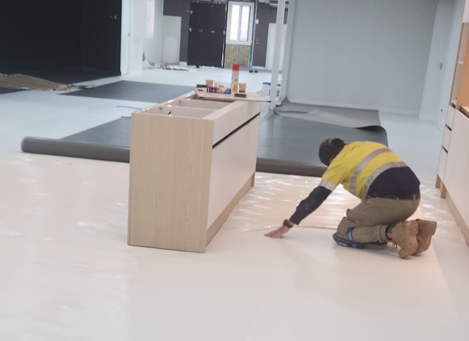 A man kneeling down on the floor in front of a table.